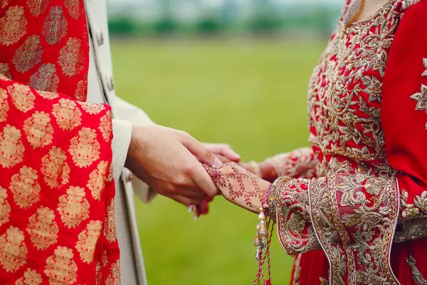 Hindu bride walks behind husband holding garb